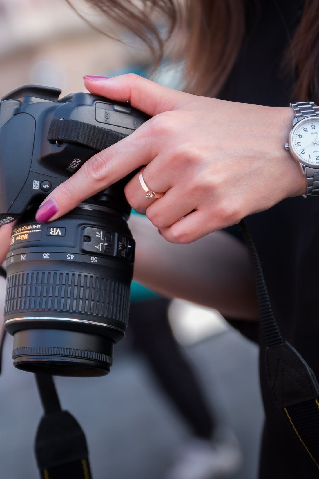 Vrouwenhand met ring en horloge om een spiegelreflexcamera