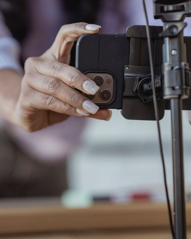 Handen zetten een telefoon op een statief voor een opname