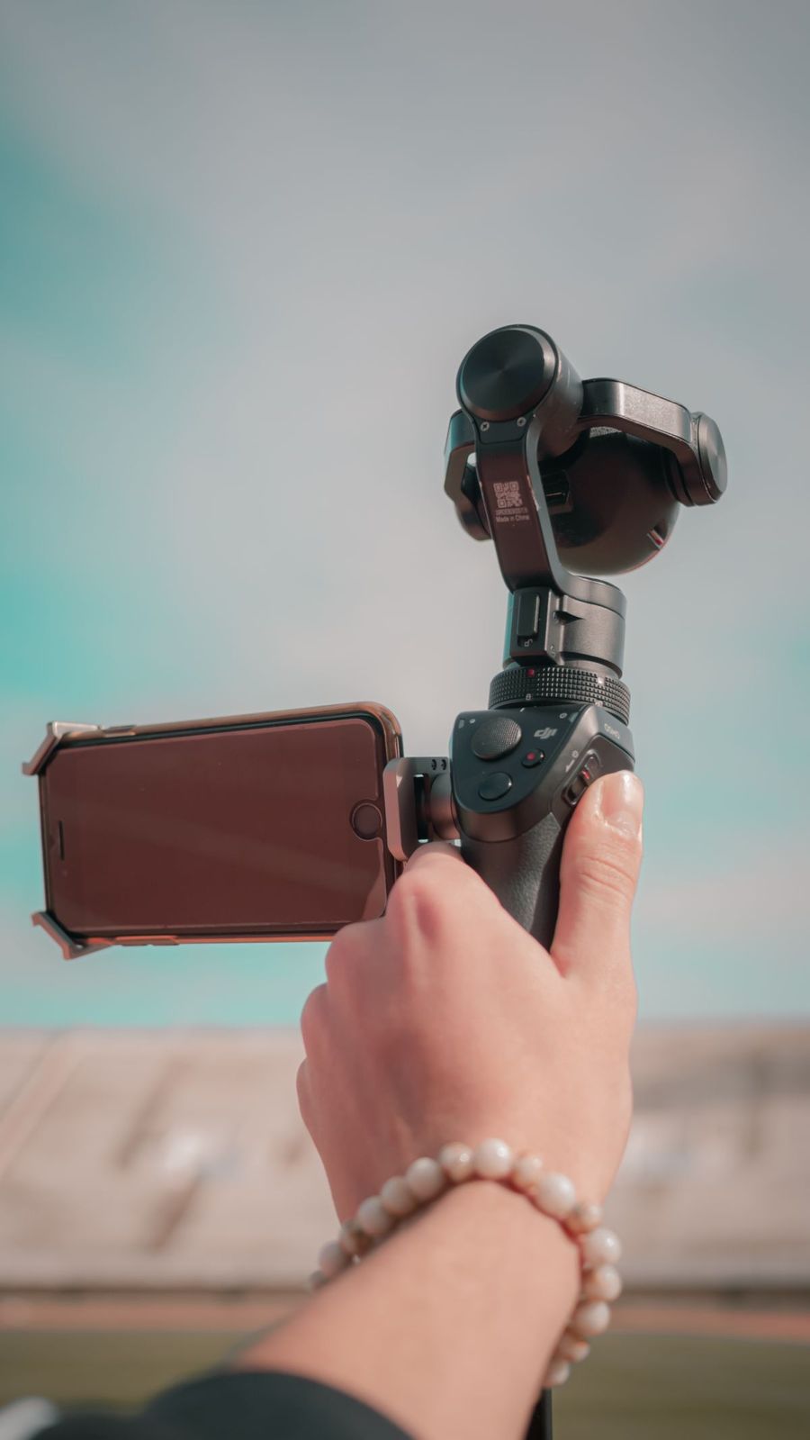 Hand met armband houdt een telefoon op een stabilisator vast